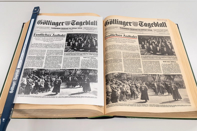 Geburtstagszeitung und Originalzeitung im Vergleich. Links eine ausgedruckte Geburtstagszeitung mit Zeitungshalter, rechts die Originalzeitung.